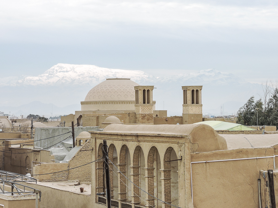 Le torri del vento di Yazd e le montagne innevate all'orizzonte viste da uno dei suoi tetti