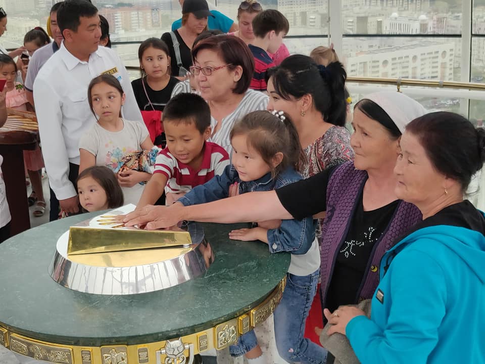 Tutti in fila per toccare il calco della mano del presidente kazako Nazarbaev sulla cima della torre bayterek